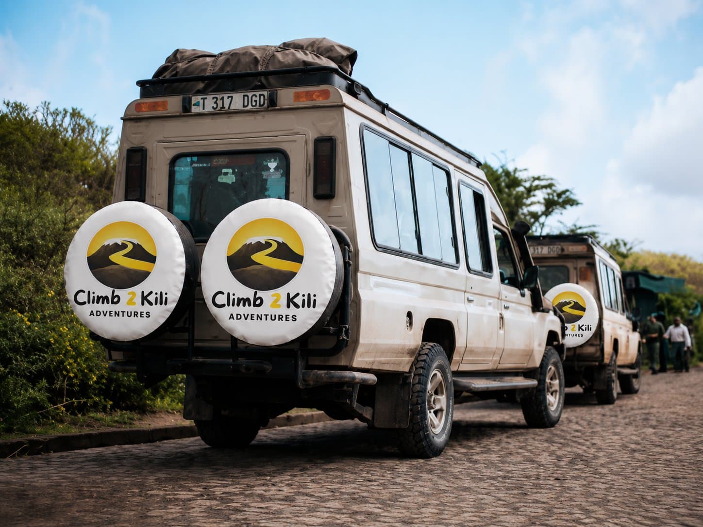 מייסד עומד עם Kilimanjaro מדריכים, נמלים, שפים, נהגים ואנשי קהילה מקומיים מתחת להר קילימנג'רו